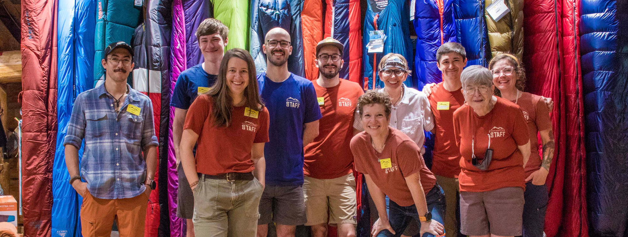 A group of staff members standing in front of sleeping bags.